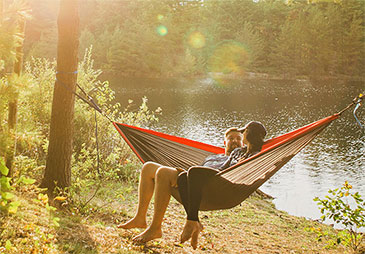 two people sitting in hammock by a lake